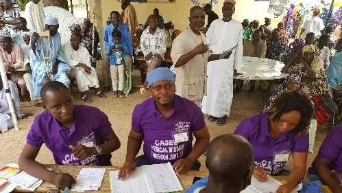 Volunteers in purple shirts registering patients at a table