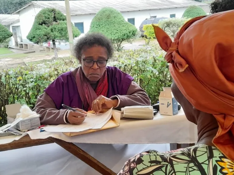 A doctor in a purple apron writing a prescription for a patient