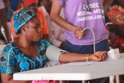 A volunteer taking a woman's blood pressure