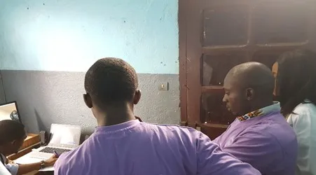 Volunteers in purple shirts watching a consultation on laptop screens