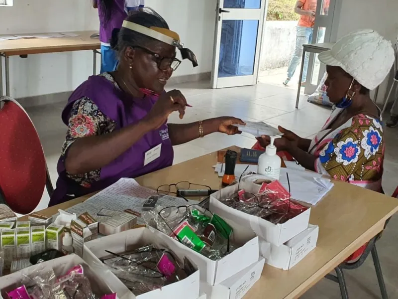 Two volunteers in purple sorting medicine at a table