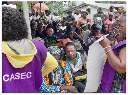 A crowd waiting, a volunteer in a CASEC shirt in front
