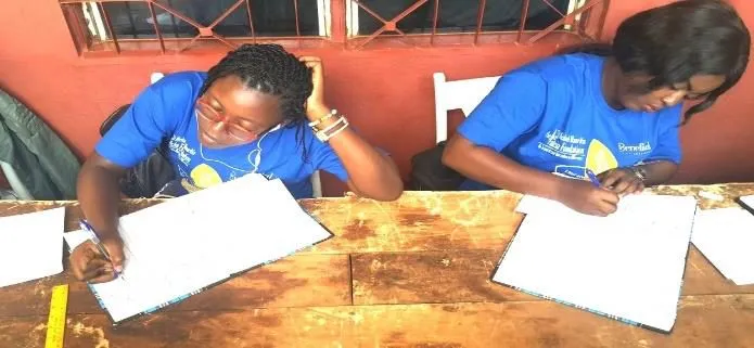 Volunteers in blue writing in registration books