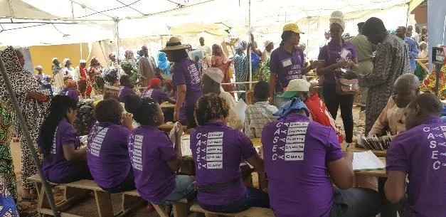 A row of volunteers in purple shirts working at tables