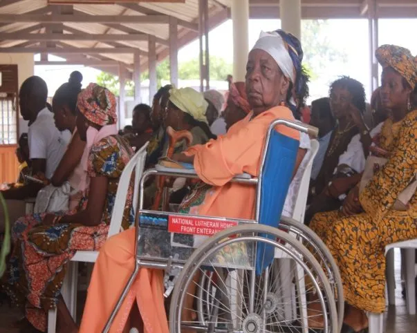 An elderly woman in a wheelchair among patients waiting their turn