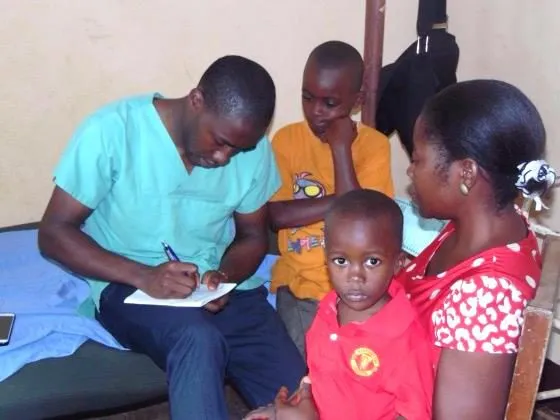A doctor writing notes beside a mother and her young children