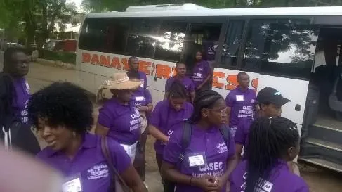 Volunteers in purple shirts beside a bus