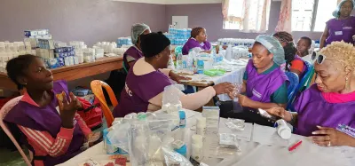 Volunteers in purple mission aprons working with patients at long tables