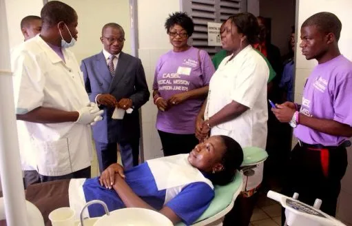 A dentist and helpers around a patient in the dental chair