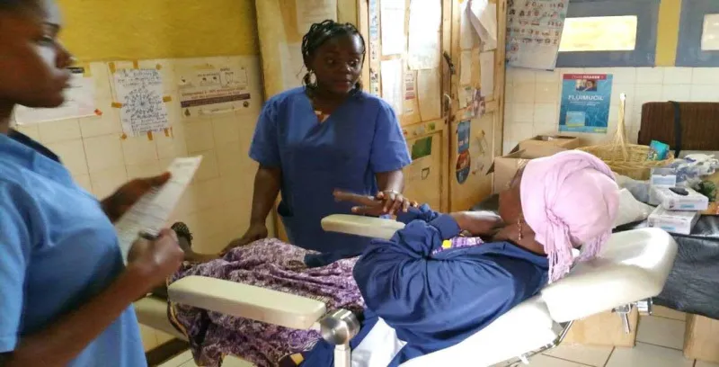 Nurses in blue tending a patient on an examination bed