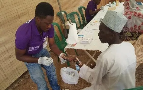 A volunteer testing a patient's blood sugar