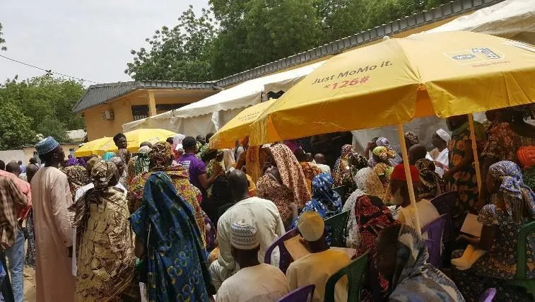 A crowd waiting under yellow umbrellas outside the hospital