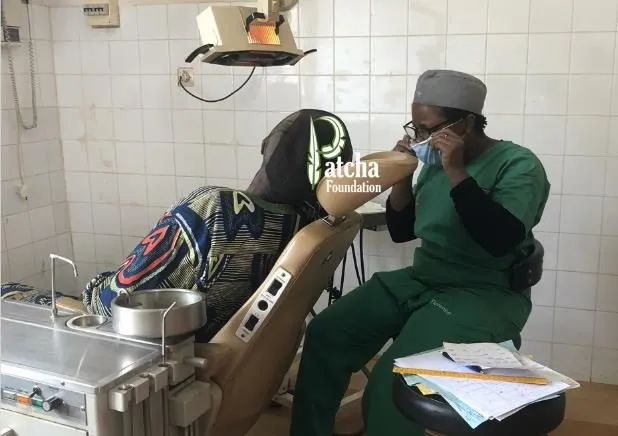 A dentist in green scrubs treating a patient