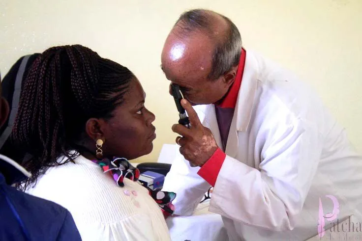 A doctor examining a woman's eyes with a hand-held light