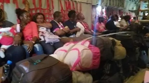 Volunteers in purple shirts travelling on a train with their bags