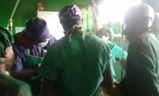 A surgical team in green scrubs at work