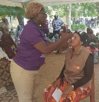 A volunteer examining a woman's eyes