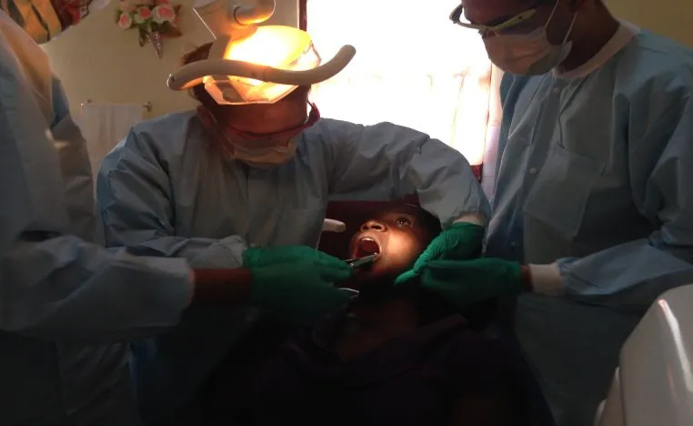 A dentist with a head lamp treating a patient