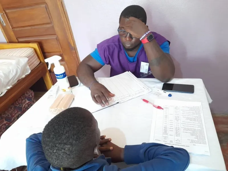 A volunteer at a desk with a young patient